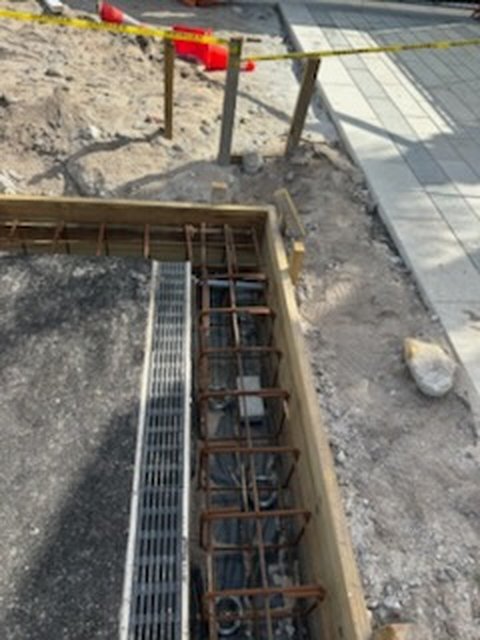 Perimeter footing formwork with rebar cage next to a trench drain at a padel court